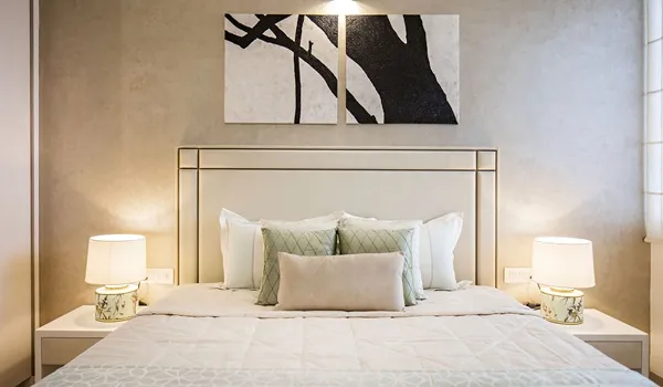 Bedroom interior with double bed, bedside lamps and abstract wall art